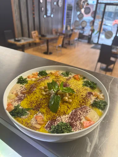 Aleppo Castle hummus bowl garnished with olive oil, herbs and olives